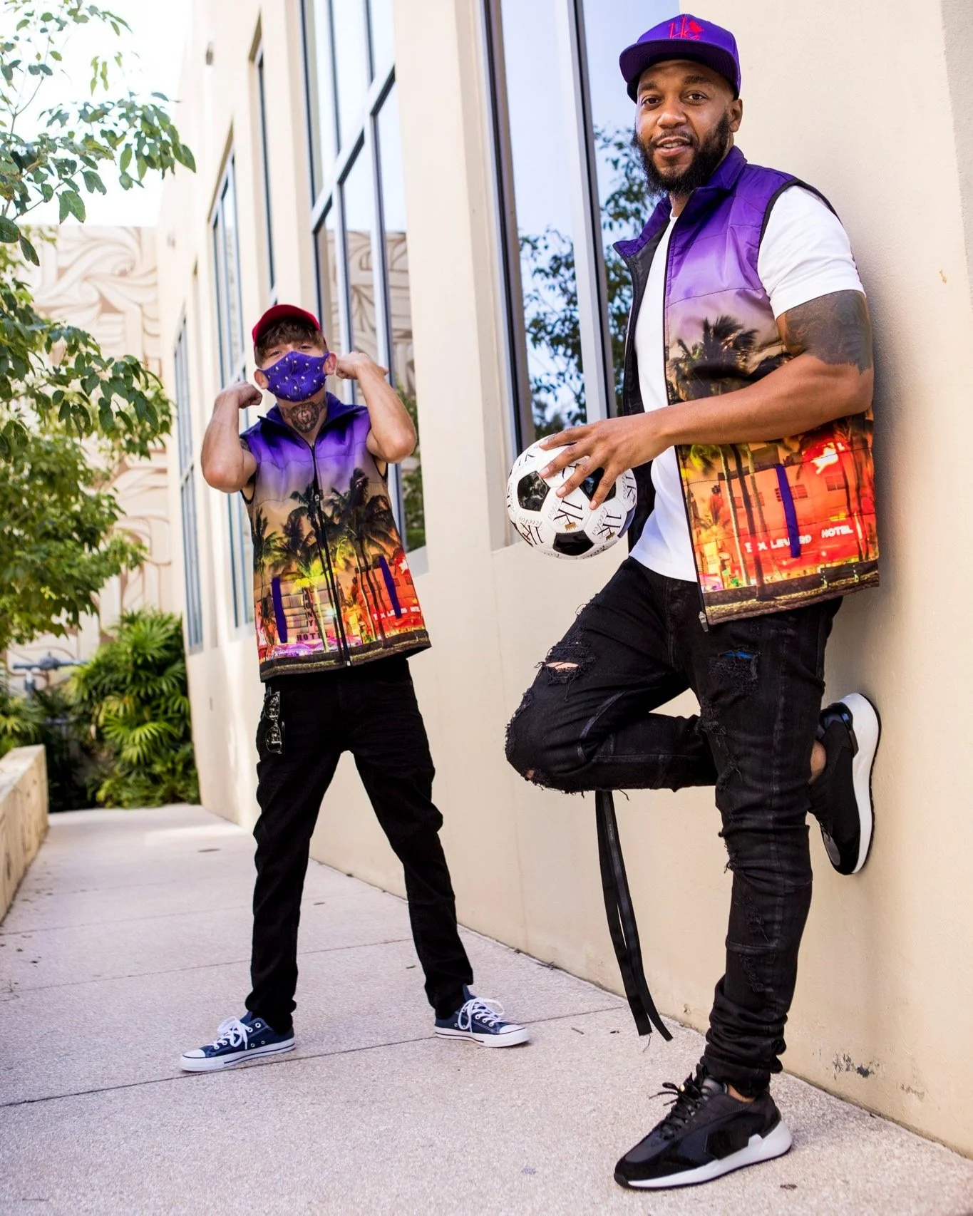Two men wearing the 1K South Beach nylon streetwear vest with a purple sunset and palm tree print in Florida