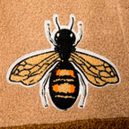 Close up of the embroidered bee patch on the 1K Bee Chenille shirt highlighting the detailed gold stitching