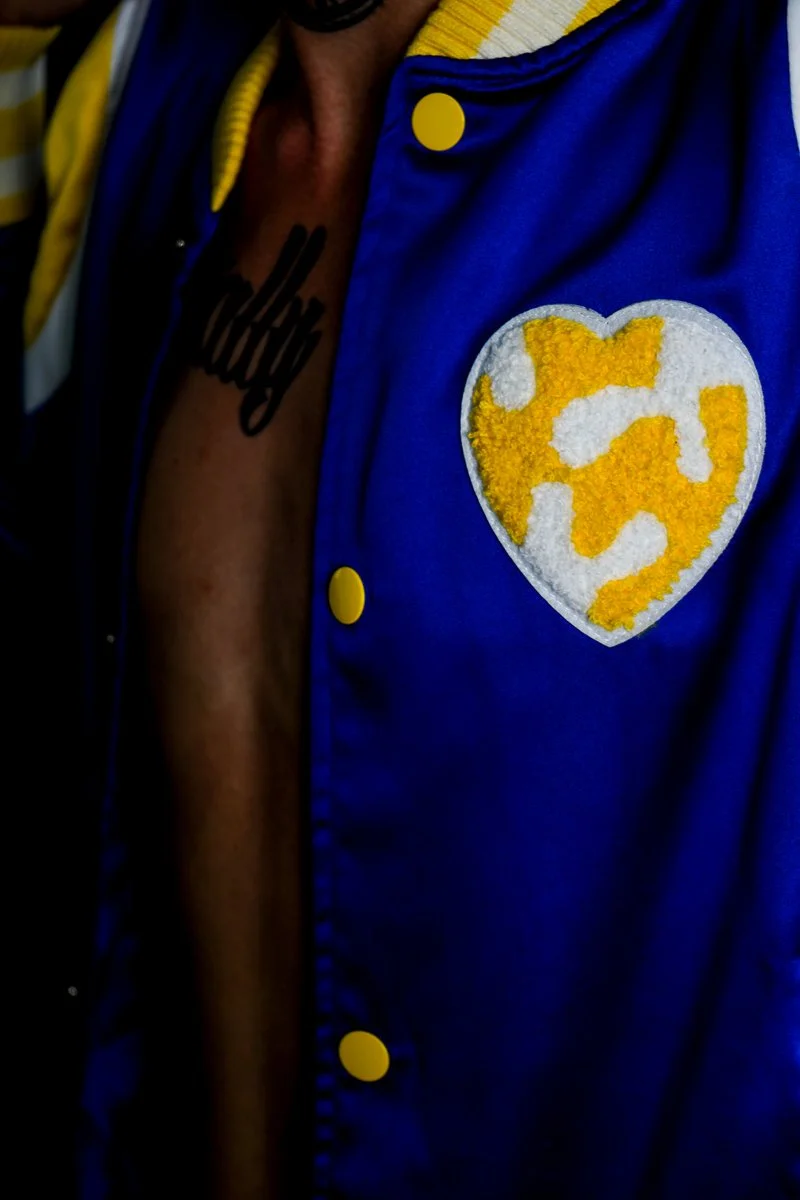 Detailed view of the heart shaped chenille patch on the royal blue satin varsity jacket